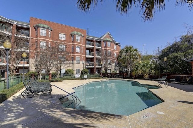 pool with a patio area and fence