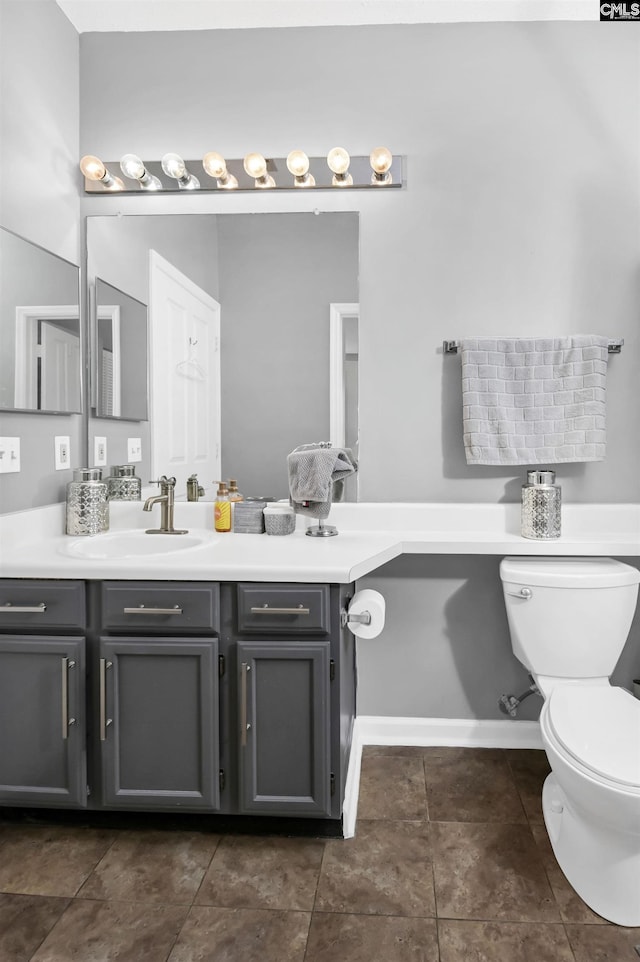 bathroom featuring vanity, toilet, baseboards, and tile patterned flooring