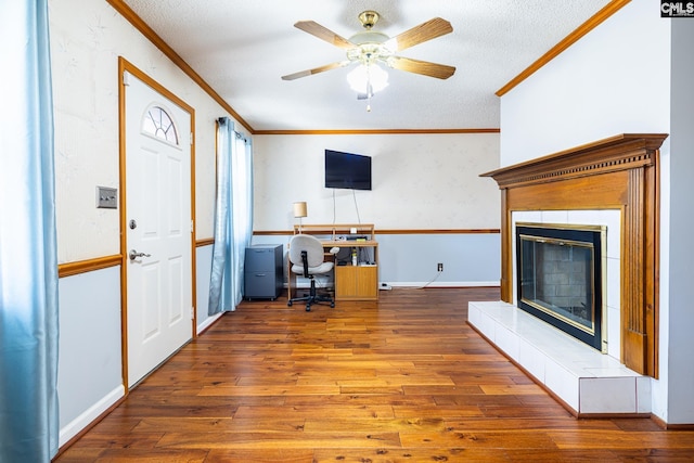 office space with ornamental molding, a ceiling fan, a textured ceiling, hardwood / wood-style floors, and a fireplace