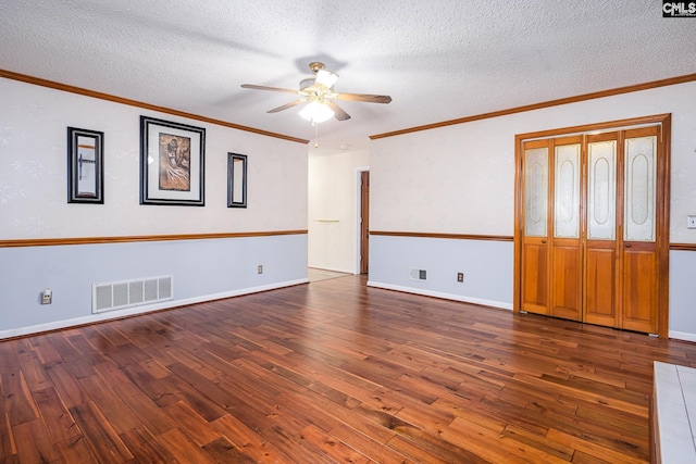 spare room featuring a textured ceiling, hardwood / wood-style flooring, visible vents, and ornamental molding