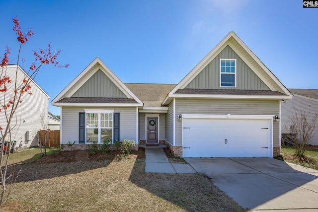 view of front of house featuring board and batten siding, fence, driveway, stone siding, and an attached garage