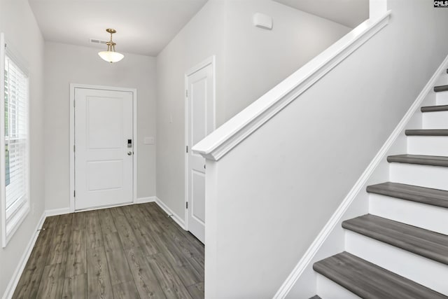 entrance foyer with visible vents, baseboards, wood finished floors, and stairs