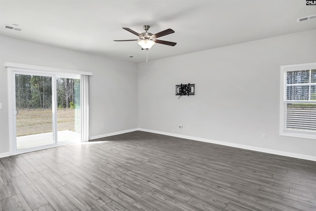 empty room with dark wood finished floors, visible vents, ceiling fan, and baseboards