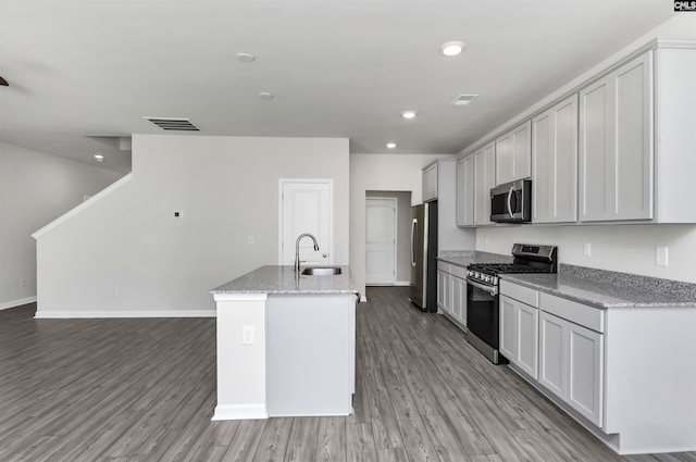 kitchen featuring visible vents, a sink, light wood-type flooring, stainless steel appliances, and a kitchen island with sink