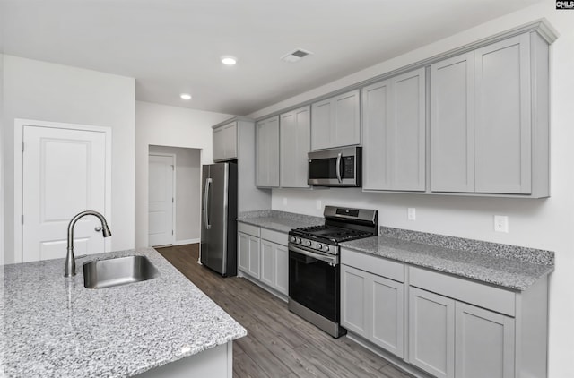 kitchen with wood finished floors, visible vents, a sink, gray cabinetry, and stainless steel appliances