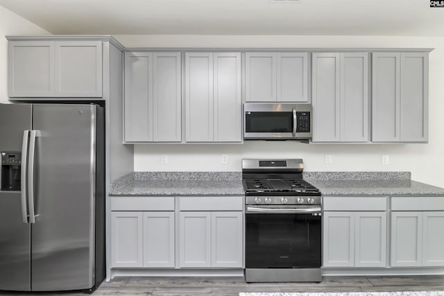 kitchen featuring visible vents, appliances with stainless steel finishes, gray cabinets, and light wood finished floors