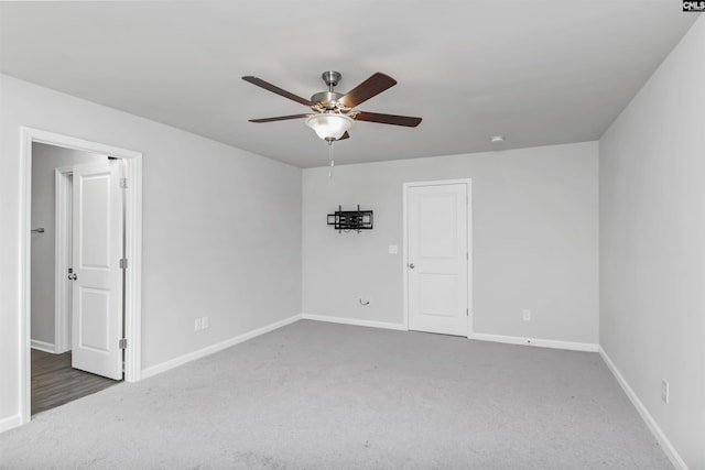 carpeted spare room featuring baseboards and ceiling fan