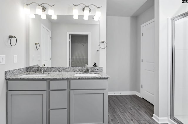 full bathroom with double vanity, wood finished floors, baseboards, and a sink