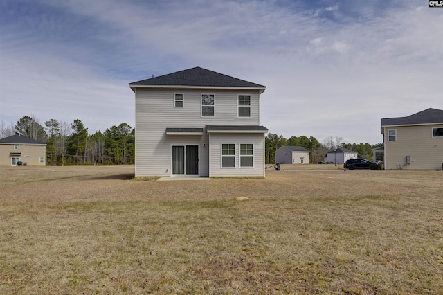 back of house featuring a yard and roof with shingles