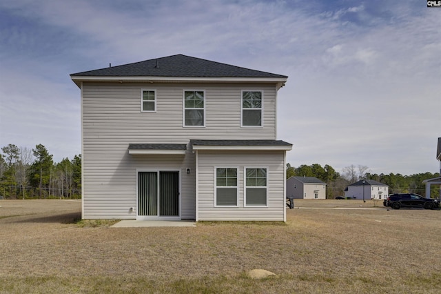 back of property featuring a lawn and a shingled roof