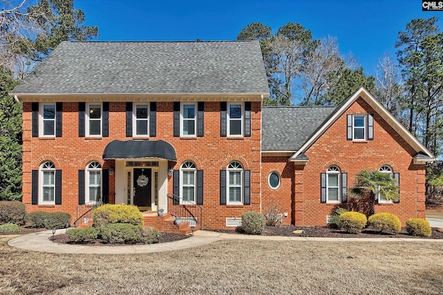 colonial house with crawl space, brick siding, and roof with shingles