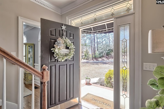 foyer entrance with wood finished floors, stairs, and ornamental molding