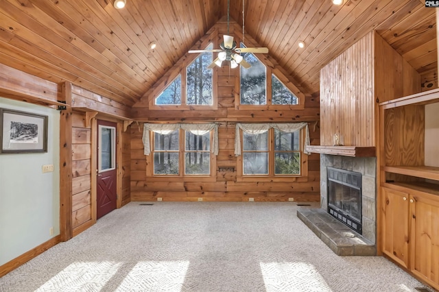 unfurnished living room featuring high vaulted ceiling, a tiled fireplace, carpet floors, wooden ceiling, and wood walls