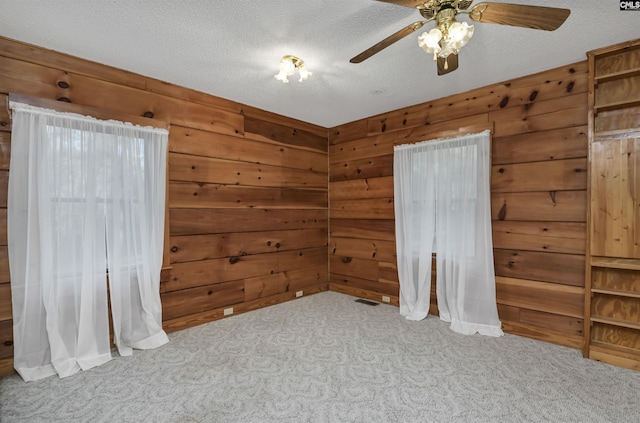 unfurnished bedroom with a textured ceiling, wood walls, and carpet