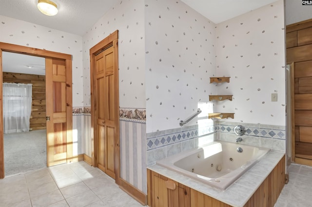 bathroom featuring tile patterned floors, a tub with jets, wainscoting, and wallpapered walls