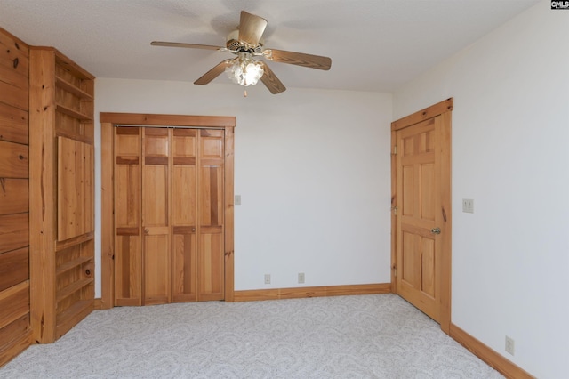 unfurnished bedroom with a closet, baseboards, carpet floors, and ceiling fan