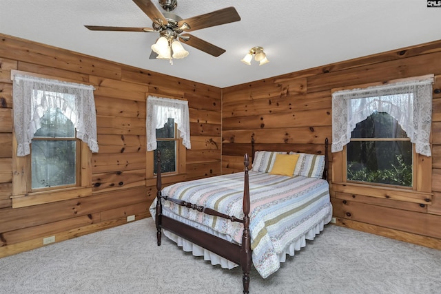 bedroom featuring ceiling fan, carpet, wood walls, and a textured ceiling