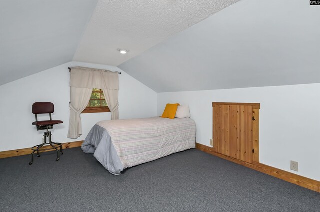 bedroom featuring vaulted ceiling, carpet flooring, baseboards, and a textured ceiling