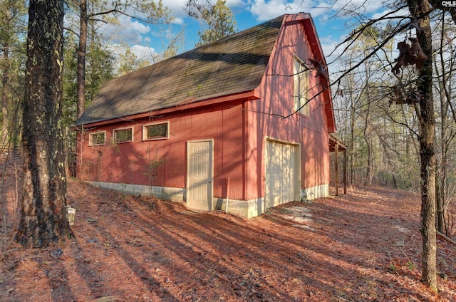 exterior space featuring a gambrel roof, an outbuilding, a barn, roof with shingles, and a garage