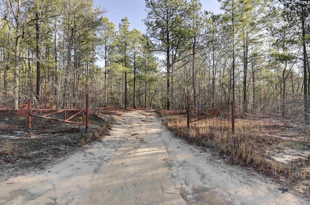 view of street featuring a wooded view and a gate