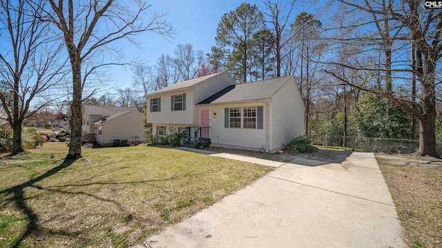 tri-level home featuring a front lawn and fence