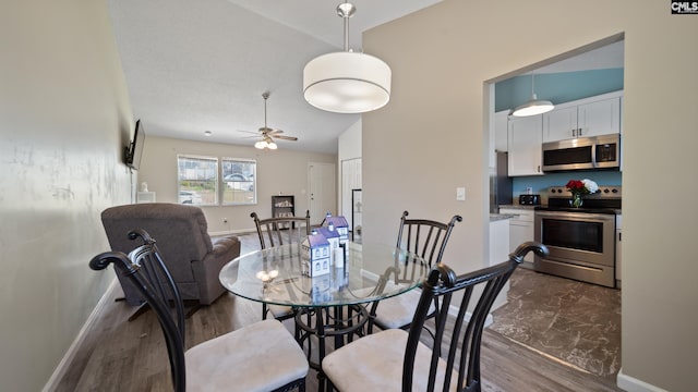 dining area with ceiling fan, baseboards, and dark wood-style flooring