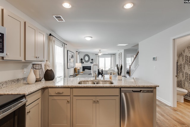 kitchen with visible vents, a healthy amount of sunlight, a peninsula, stainless steel dishwasher, and a sink