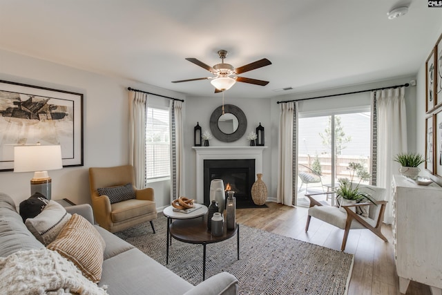 living area with light wood-style flooring, a fireplace with flush hearth, a healthy amount of sunlight, and visible vents