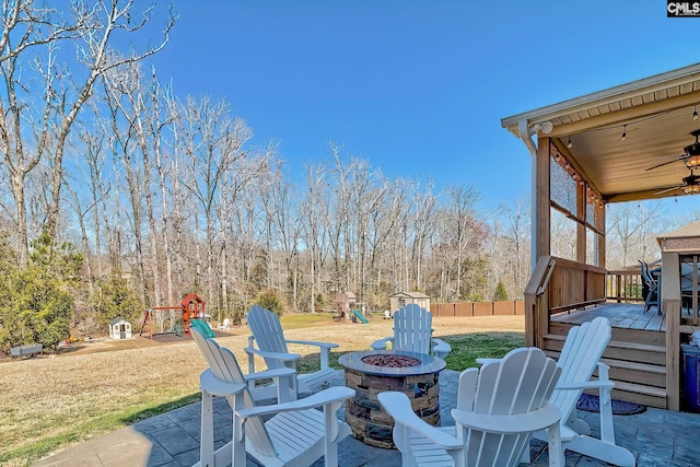 view of patio / terrace featuring a deck, a fire pit, ceiling fan, and fence