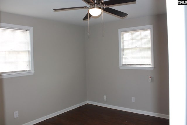 spare room with baseboards, dark wood-type flooring, and ceiling fan