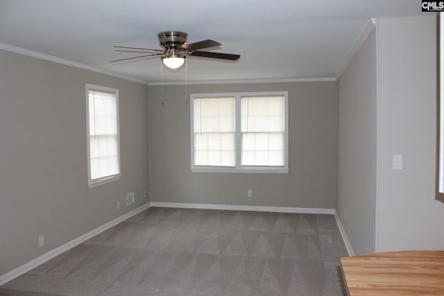 carpeted empty room with visible vents, a ceiling fan, crown molding, and baseboards