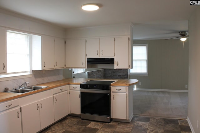 kitchen with a sink, under cabinet range hood, white cabinets, and electric stove