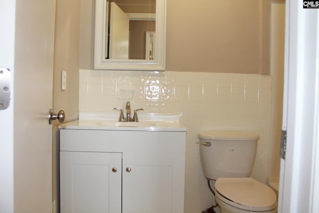 bathroom with vanity, tile walls, and toilet