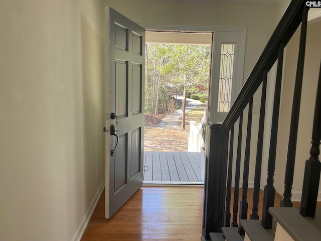 foyer entrance featuring stairs, baseboards, and wood finished floors