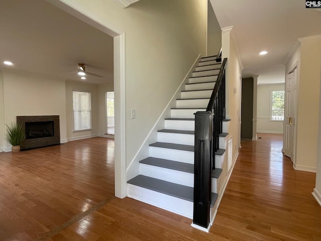 staircase with wood finished floors, baseboards, a fireplace, recessed lighting, and ceiling fan