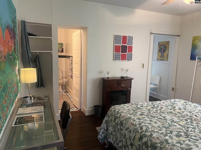 bedroom with ensuite bathroom, baseboards, and wood finished floors