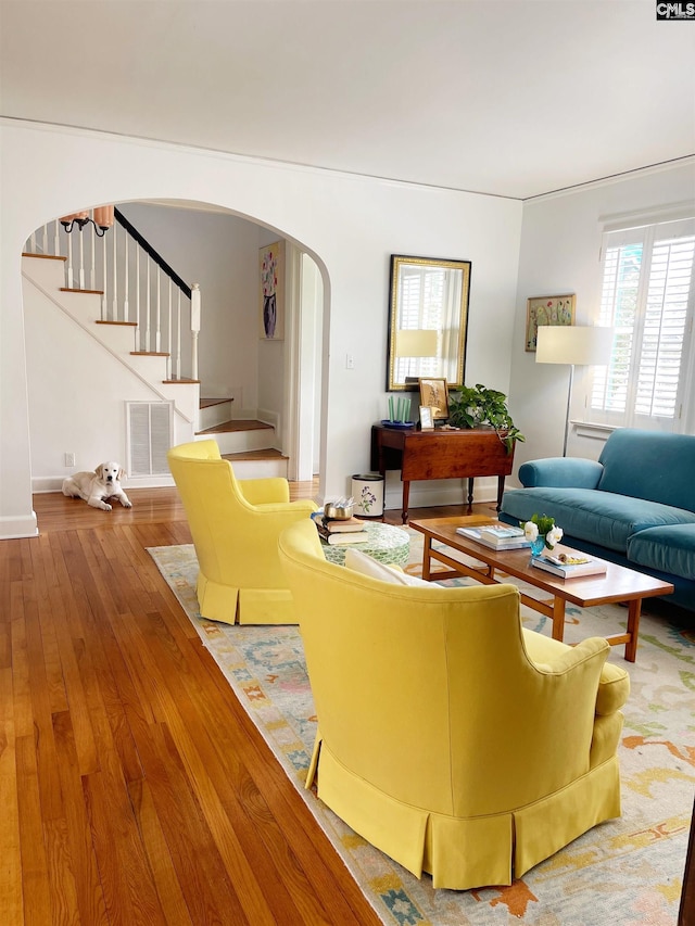 living area with stairway, visible vents, arched walkways, and wood-type flooring