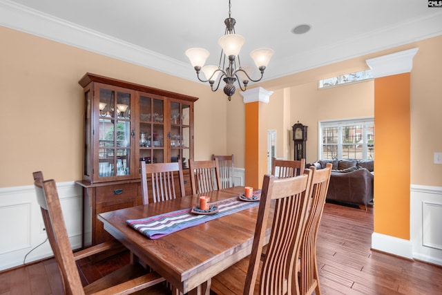 dining space with a chandelier, a wainscoted wall, wood finished floors, and crown molding