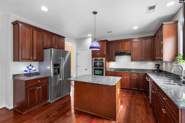 kitchen featuring visible vents, a sink, under cabinet range hood, appliances with stainless steel finishes, and dark wood-style flooring