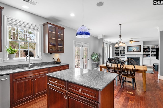 kitchen featuring visible vents, a sink, dark wood finished floors, a fireplace, and dishwasher