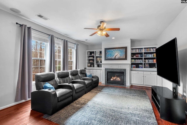 living room with visible vents, ceiling fan, baseboards, wood finished floors, and a glass covered fireplace