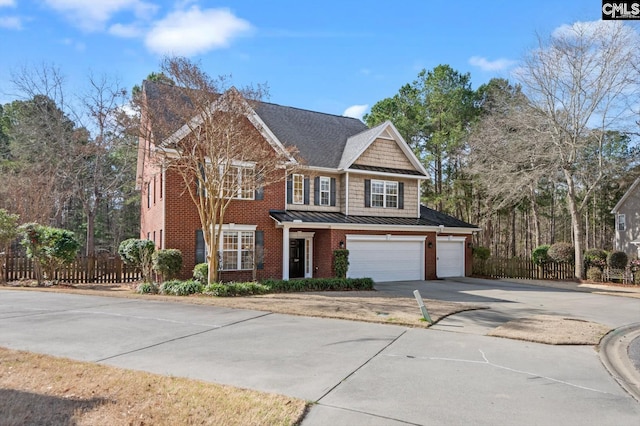 view of front of home with fence, driveway, a standing seam roof, brick siding, and metal roof