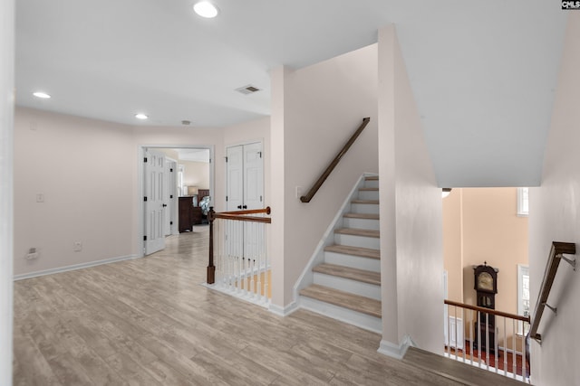 stairs featuring recessed lighting, visible vents, baseboards, and wood finished floors