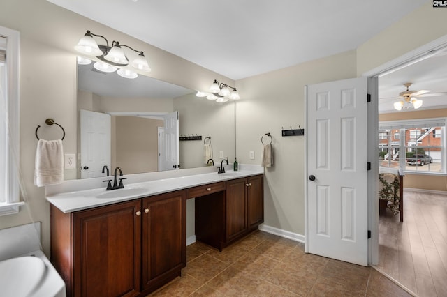 full bathroom featuring ceiling fan, double vanity, baseboards, and a sink