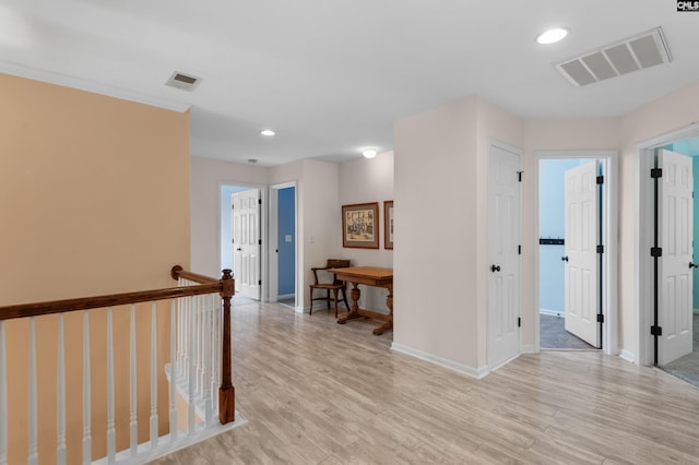 hallway featuring light wood finished floors, visible vents, and baseboards