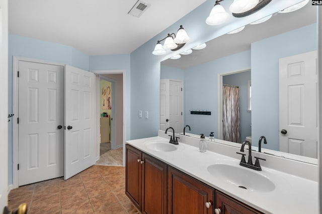 bathroom with tile patterned flooring, visible vents, double vanity, and a sink