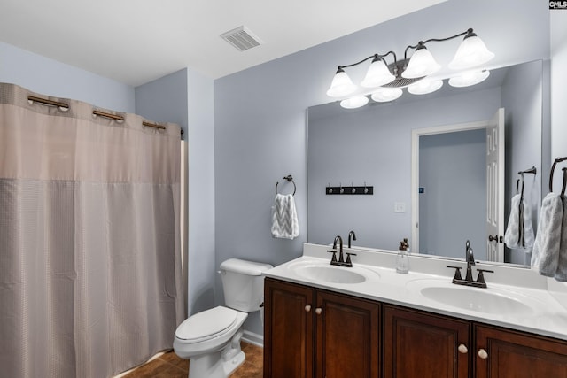 bathroom featuring double vanity, toilet, visible vents, and a sink