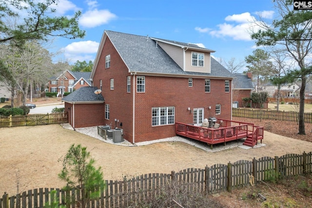 rear view of house with cooling unit, a deck, brick siding, and a fenced backyard