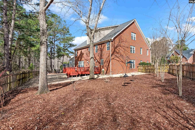 exterior space with a wooden deck, brick siding, and a fenced backyard