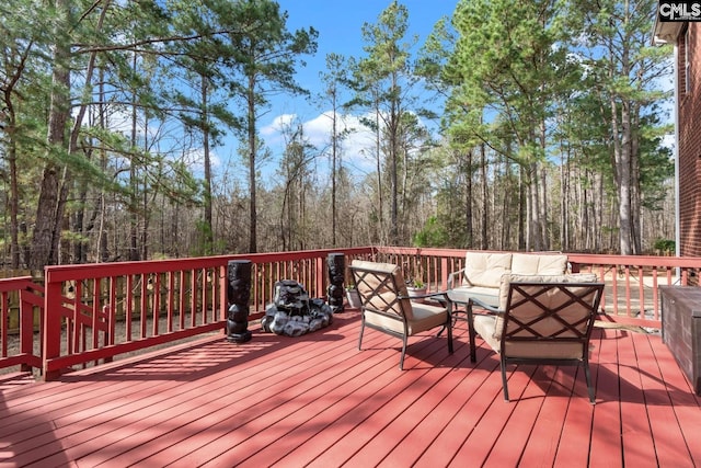 wooden terrace with a view of trees and outdoor lounge area